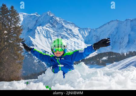 Il ragazzo gioca in piedi con le mani alzate nella nevicata Foto Stock