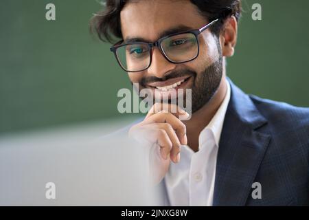 Felice arabo indiano giovane uomo d'affari che lavora guardando il computer. Foto Stock