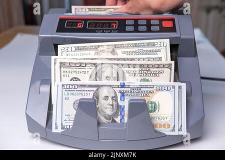 La macchina di contatore di denaro elettronica sta contando le banconote in dollari americani. Concetto di finanza e cassa. Foto Stock