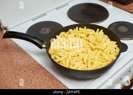 Le patate crude vengono fritte in una pentola Foto Stock