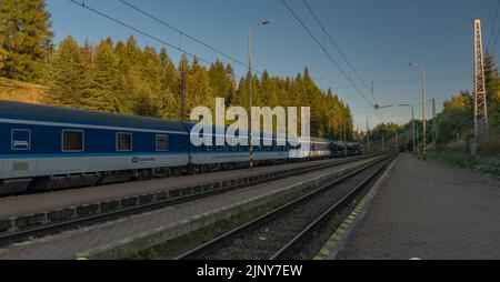 Treni alla stazione di Strba sotto le montagne Vysoke Tatry in estate mattina Foto Stock