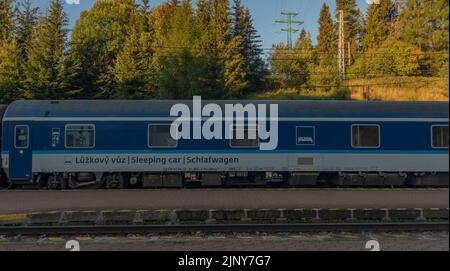 Treni alla stazione di Strba sotto le montagne Vysoke Tatry in estate mattina Foto Stock