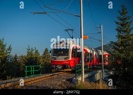 Treni alla stazione di Strba sotto le montagne Vysoke Tatry in estate mattina Foto Stock