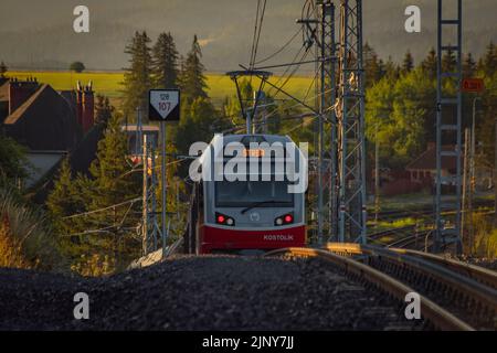 Treni alla stazione di Strba sotto le montagne Vysoke Tatry in estate mattina Foto Stock