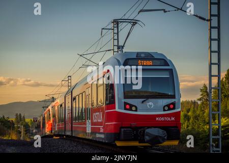 Treni alla stazione di Strba sotto le montagne Vysoke Tatry in estate mattina Foto Stock