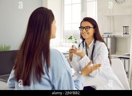 Medico amichevole che ascolta la sua paziente femminile alla riunione di consultazione in ospedale ufficio. Foto Stock