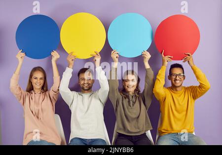 Giovani persone multirazziali seduti in fila e tenendo colorate bolle di discorso rotondo con spazio copia. Foto Stock