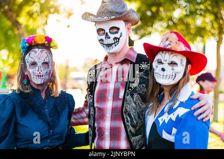 Una famiglia di tre persone vestita con costumi di Halloween da teschio di zucchero in stile occidentale in occasione di una festa di Halloween a Fountain Hills, Arizona, USA. Foto Stock