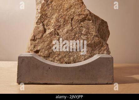 Un podio in cemento per la presentazione del prodotto su uno sfondo di pietra beige. Il piedistallo è realizzato in materiale naturale. Disposizione per mostre. Foto di alta qualità Foto Stock