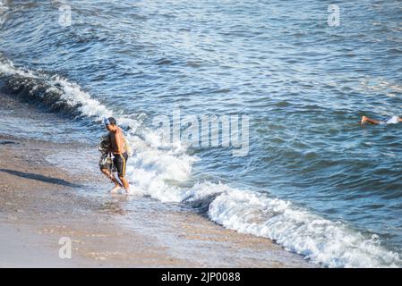 Salvador, Bahia, Brasile - 01 novembre 2021: Pescatore che lascia il mare con la rete di pesca alla spiaggia di Rio Vermelho a Salvador, Bahia. Foto Stock