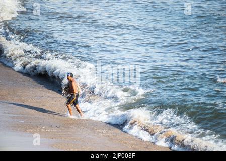 Salvador, Bahia, Brasile - 01 novembre 2021: Pescatore che lascia il mare con la rete di pesca alla spiaggia di Rio Vermelho a Salvador, Bahia. Foto Stock