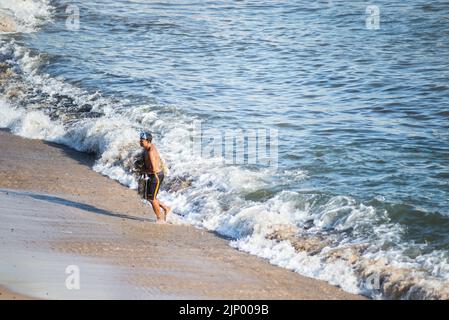 Salvador, Bahia, Brasile - 01 novembre 2021: Pescatore che lascia il mare con la rete di pesca alla spiaggia di Rio Vermelho a Salvador, Bahia. Foto Stock