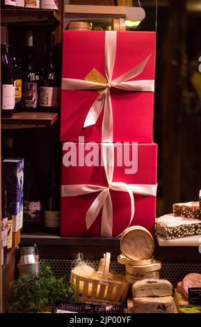 Colmar, Francia - 13 dicembre 2021: Due pacchetti regalo rossi con arco nella vetrina di un negozio di alimentari a Colmar. Foto Stock