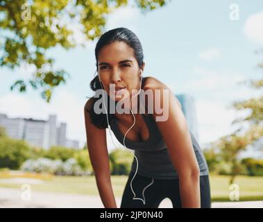 Stanco ma non sconfitto. Un giovane sportivo attraente che prende una pausa dal fare esercizio all'aperto. Foto Stock