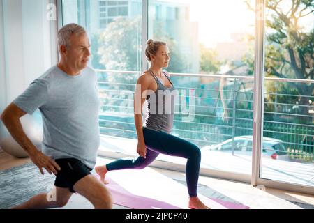 Allunga correttamente, eviti la ferita. Una coppia matura che allunga sui tappetini di yoga prima dell'allenamento fuori a casa. Foto Stock