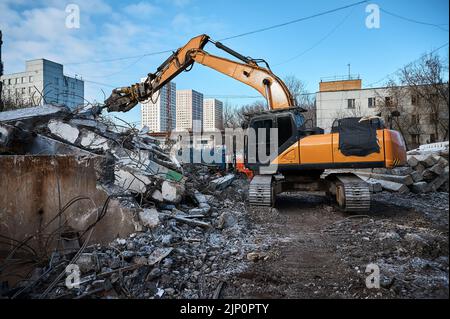 L'escavatore con forbici idrauliche taglia travi in calcestruzzo Foto Stock