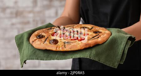 Donna con focaccia tradizionale italiana, primo piano Foto Stock