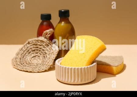 Spugne e bottiglie per la casa su sfondo colorato Foto Stock