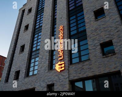 Logo Lieferando sull'esterno di un edificio. Segno illuminato del servizio di consegna del cibo nella capitale. Una marca della società appena Eat Takeaway. Foto Stock