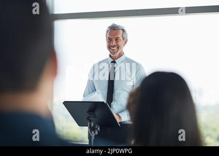 Parlare con poise e scopo. Un bell'uomo d'affari maturo che parla ad una conferenza di affari. Foto Stock