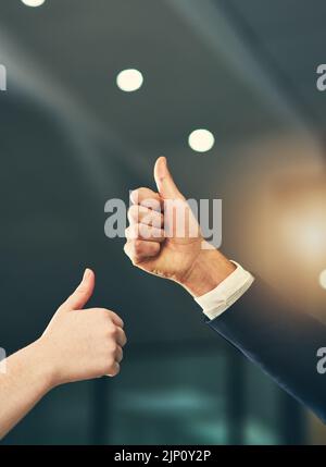 Il lavoro è ottimo e ci sono due uomini d'affari che si danno i pollici in un ufficio moderno. Foto Stock