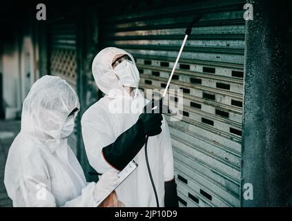 Operatori sanitari che disinfettano un edificio durante la pandemia di covid o lo puliscono per prevenire la diffusione di infezione. Igienizzatore spray specializzato Foto Stock