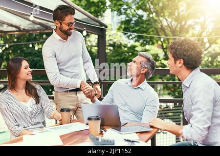 Il loro team continua a crescere e a crescere. Due uomini d'affari si stringono le mani durante una riunione all'aperto. Foto Stock