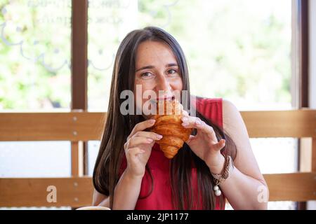 Giovane bella donna che mangia croissant Foto Stock