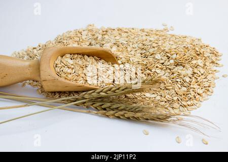 piatti di avena arrotolati non cotti con scope di legno su sfondo bianco Foto Stock