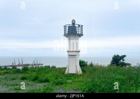 faro automatico con luce a settore su un alto promontorio sopra il porto marittimo Foto Stock