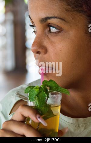 Una donna cubana di 22 anni, attraente, sorseggiando il vostro cocktail Mojito mentre guardate il tramonto del sole. Un altro bellissimo tramonto a Varadero Beach, Cuba. Foto Stock