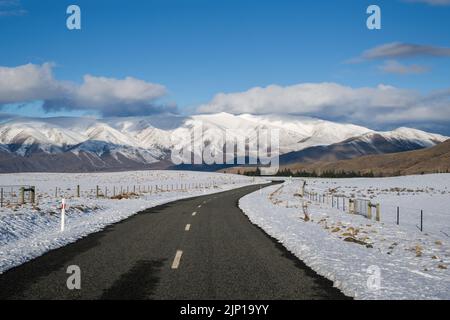 Strada del lago Ohau che conduce verso le catene montuose innevate, Twizel, South Island. Foto Stock