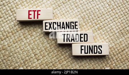 Fondi comuni di investimento vs. Simbolo ETF. Cubi con le parole ETF Exchange Traded Fund e Mutual Funds. Splendido sfondo beige. Foto Stock