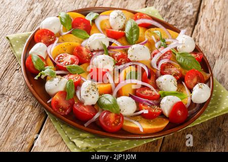 Insalata di basilico con pomodoro e pesca, primo piano su sfondo rustico in legno. Orizzontale Foto Stock