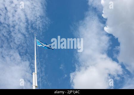 Croce di Sant'Andrea, saluta, bandiera di Scozia che sbatte sul palcoscenico contro lo sfondo del cielo blu e delle nuvole di luce a Bannockburn, scena di battaglia. Foto Stock