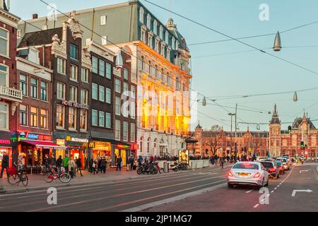 AMSTERDAM, PAESI BASSI - 12 MARZO 2015: Vista al tramonto del famoso Damrak con negozi, hotel e barche sui canali ad Amsterdam, Paesi Bassi Foto Stock