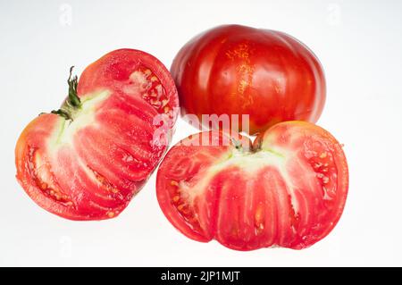 Due pomodori - un pomodoro grande rosso maturo tagliato a metà Foto Stock