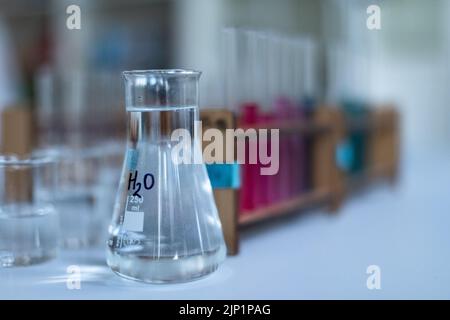 Primo piano delle coppette di misurazione e della provetta per analisi nel laboratorio chimico. Foto Stock