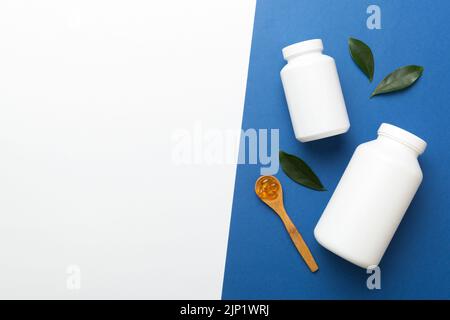 Le capsule di Omega-3 si trovano in un flacone bianco su un tavolo con il fondo verde delle foglie. Compresse di olio di pesce. Additivi biologicamente attivi omega 6, omega 9, vitam Foto Stock