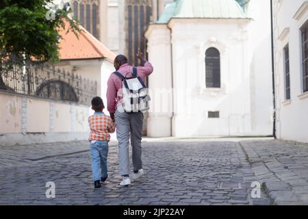 Il padre multirazziale con il figlio che viaggia insieme, camminando nel centro storico della città. Foto Stock