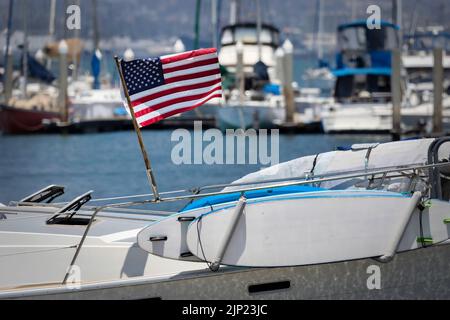 Una bandiera americana soffia al vento su una barca a vela a Glorietta Bay a Coronado, California. Foto Stock