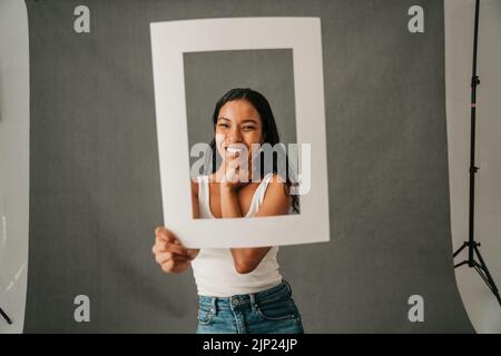Ragazza afro-americana incornicia il viso con una cornice bianca Foto Stock