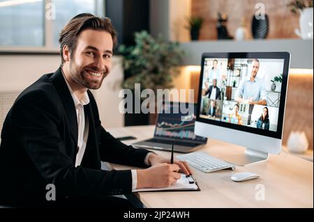 Uomo d'affari caucasico, conduce brainstorming con il team aziendale multirazziale, discutendo la strategia finanziaria e l'analisi dei rischi, guarda la fotocamera, sorridere. Conversazione tramite videoconferenza, briefing finanziario Foto Stock