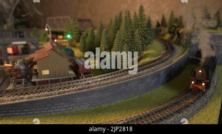 Locomotive a vapore che corrono su un modello di ferrovia. Treni passeggeri e merci che attraversano la stazione ferroviaria in miniatura. Foto Stock