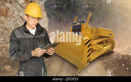 L'ingegnere programma un bulldozer autonomo utilizzando un tablet digitale Foto Stock