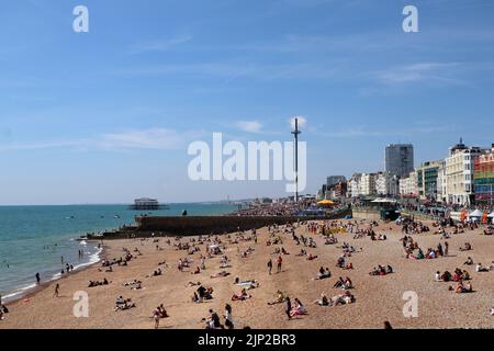 La gente si gode la spiaggia vicino al Brighton Palace Pier Foto Stock