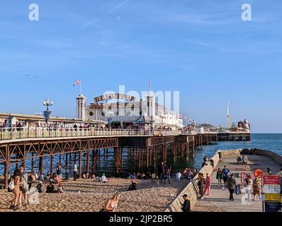 La gente si gode la spiaggia vicino al Brighton Palace Pier Foto Stock