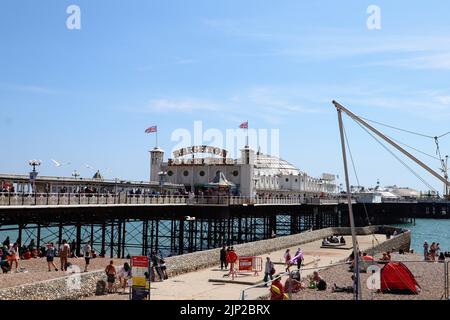 La gente si gode la spiaggia vicino al Brighton Palace Pier Foto Stock