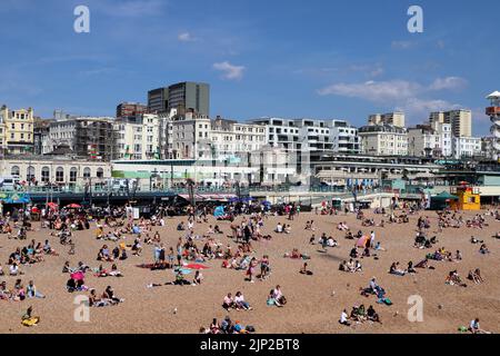 La gente si gode la spiaggia vicino al Brighton Palace Pier Foto Stock