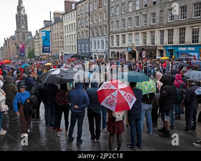 Royal Mile, Edimburgo, Scozia, Regno Unito. 15th agosto 2022. Il primo EdFringe Rain per il 2022 non ha smorzato gli spiriti del Street performer The Encourageable Rogue o il suo pubblico sulla High Street. Ha appena deciso di spogliarsi fino alle mutande e continuare. La pioggia pesante ha cominciato appena dopo 1pm. Temperatura 19 gradi centigradi. Credit: ArchWhite/alamy live news. Foto Stock